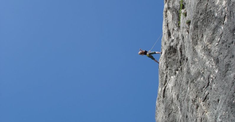 Risk - Man Standing on Rock Against Clear Blue Sky