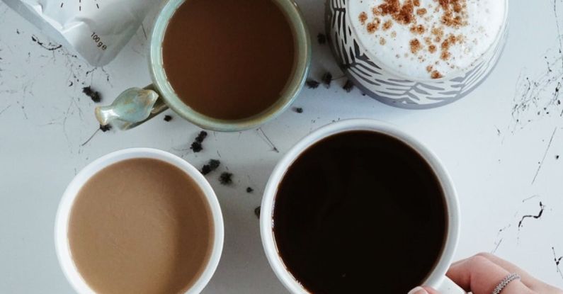 Types - Woman Hand with Different Coffee Types in Mugs on Table